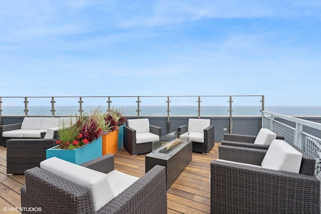 deck featuring a water view and an outdoor living space with a fire pit