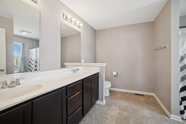 full bathroom with a sink, baseboards, toilet, and double vanity