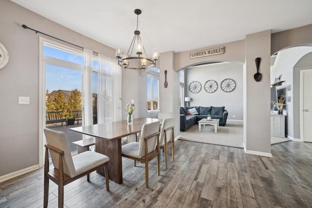 dining room featuring a notable chandelier, wood finished floors, arched walkways, and baseboards