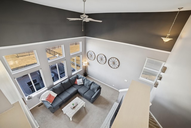 living room featuring ceiling fan, baseboards, carpet, and a towering ceiling