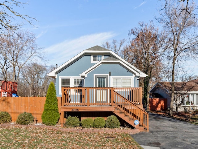 view of front of home with a wooden deck, fence, and stucco siding