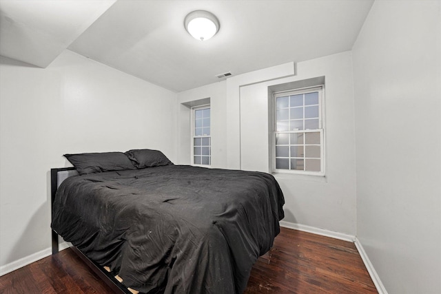 bedroom with wood finished floors, visible vents, and baseboards