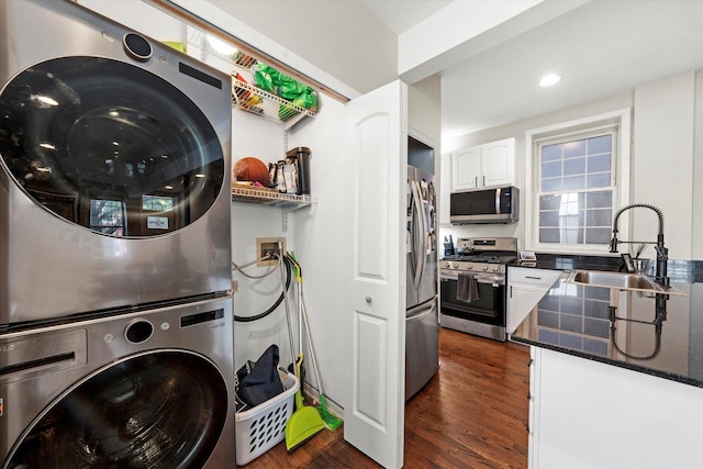 laundry area with dark wood finished floors, laundry area, stacked washer / drying machine, and a sink