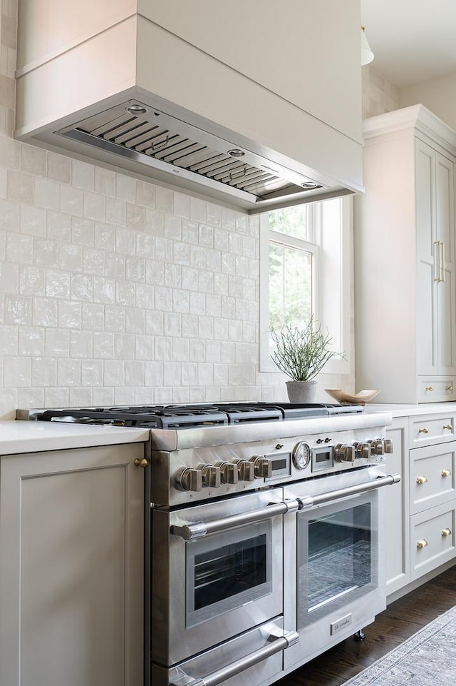 4489 Central Ave, Western Springs, IL 60558 - kitchen with double oven range, wall chimney exhaust hood, light countertops, white cabinetry, and decorative backsplash