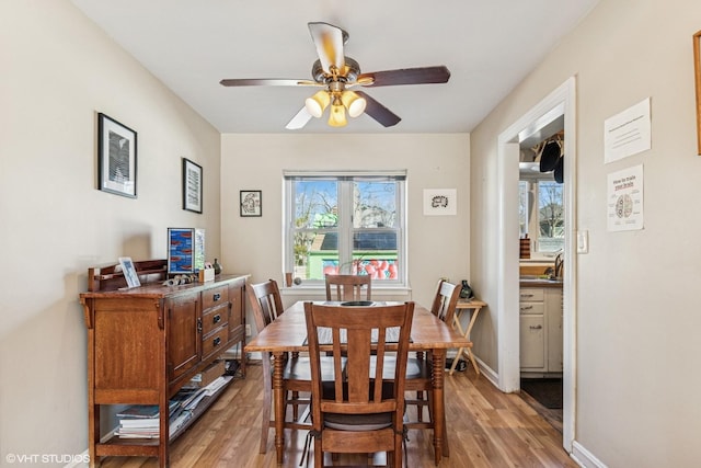 dining area with baseboards, ceiling fan, and light wood finished floors