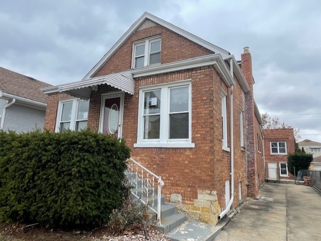 view of front of house featuring brick siding and a chimney