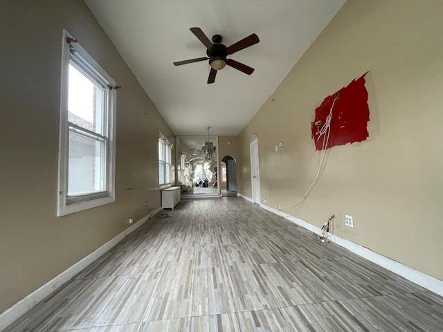 unfurnished living room featuring a ceiling fan, radiator, wood finished floors, and baseboards