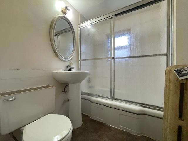 bathroom with toilet and shower / bath combination with glass door