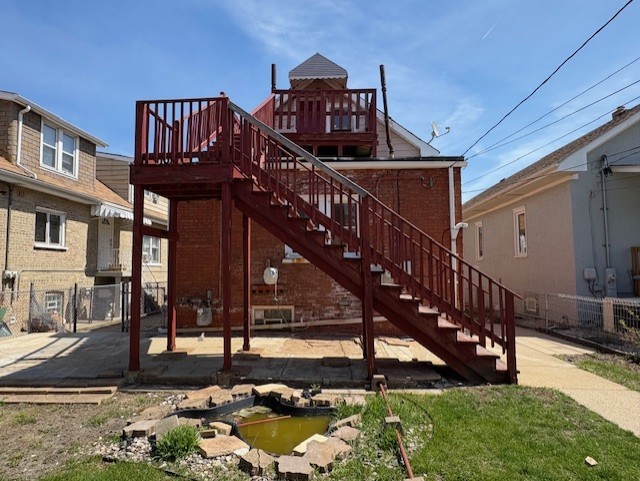 back of property featuring brick siding, fence, and stairway