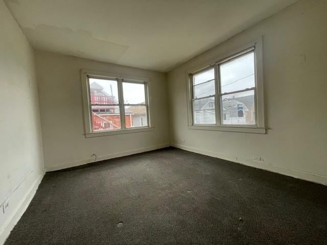 empty room with baseboards and dark colored carpet