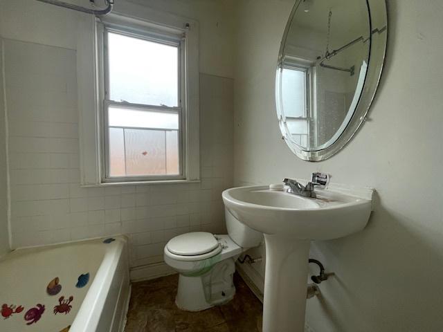 bathroom featuring a tub to relax in, toilet, a shower, and a healthy amount of sunlight