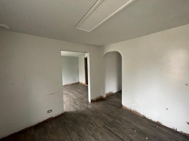 empty room with arched walkways and wood finished floors