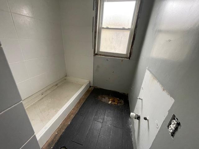 full bath featuring hardwood / wood-style flooring and a tile shower