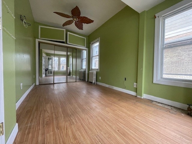 spare room with ceiling fan, radiator heating unit, baseboards, and wood finished floors