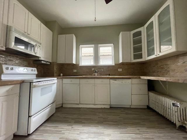 kitchen featuring white cabinetry, white appliances, decorative backsplash, and a sink