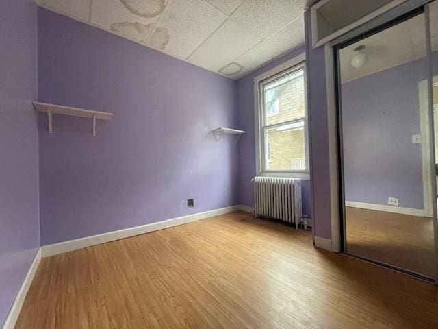 unfurnished room with baseboards, wood finished floors, and radiator heating unit