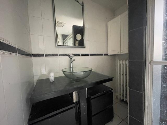 bathroom with tile patterned floors, tasteful backsplash, radiator heating unit, tile walls, and vanity