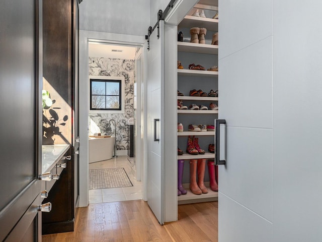 spacious closet featuring light wood-style floors and a barn door