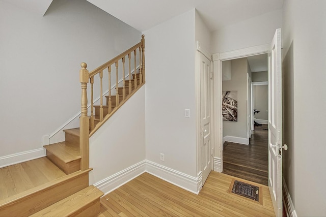 stairs with wood finished floors, visible vents, and baseboards