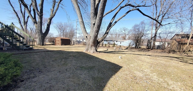 view of yard with an outdoor structure, stairway, and a storage unit