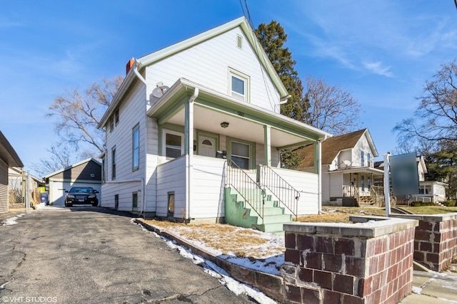 view of front of home with aphalt driveway, covered porch, and an outdoor structure