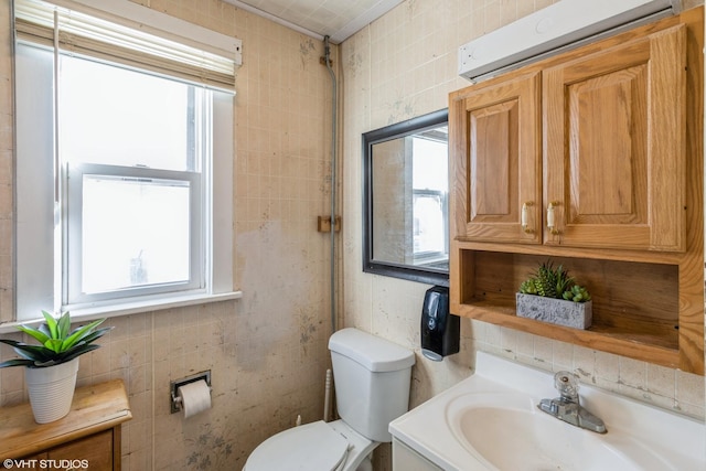 bathroom with vanity, tile walls, an AC wall unit, and toilet