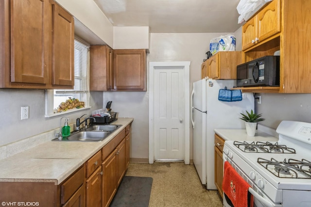 kitchen featuring black microwave, light countertops, white range with gas cooktop, brown cabinets, and a sink