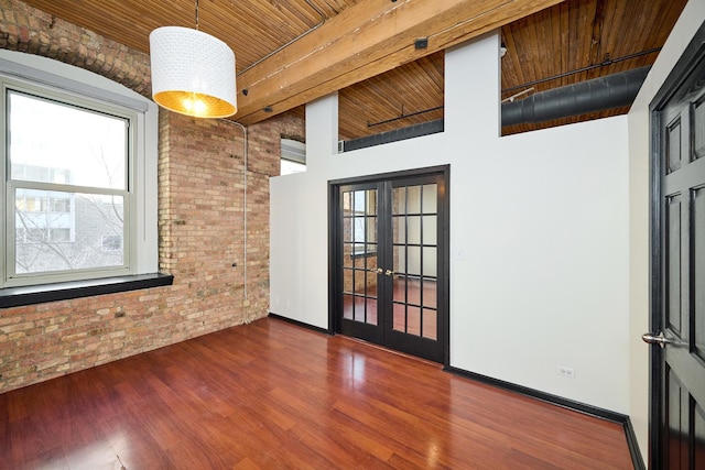 unfurnished room featuring plenty of natural light, brick wall, french doors, and wood finished floors