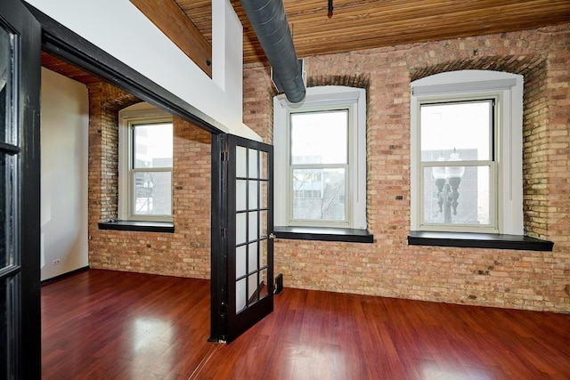 spare room with dark wood-style floors, brick wall, and wood ceiling