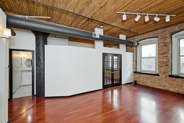 spare room with brick wall, wooden ceiling, and wood finished floors