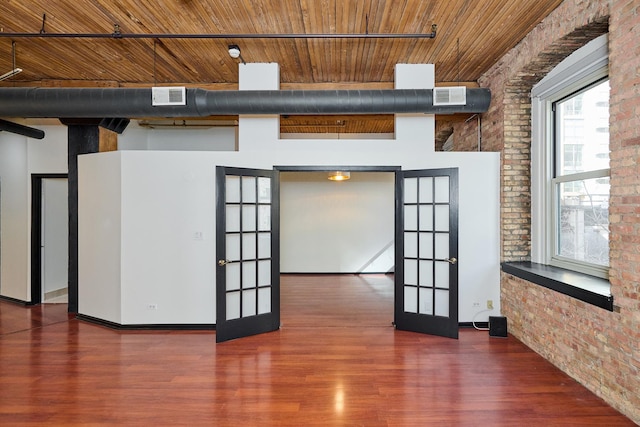 spare room featuring french doors, wood finished floors, brick wall, and wooden ceiling