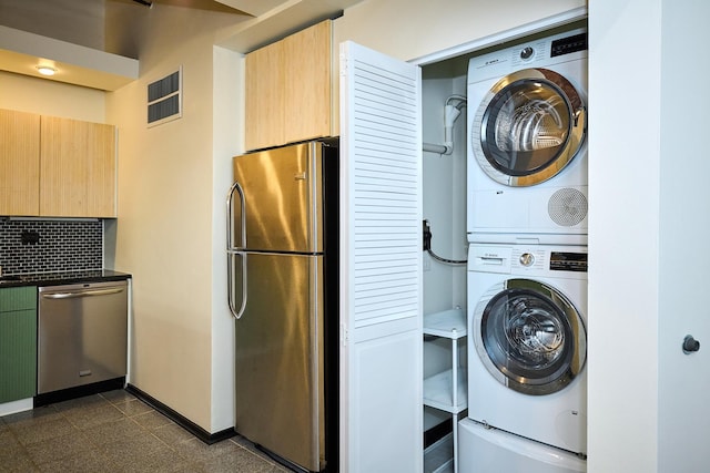 laundry room featuring visible vents, granite finish floor, stacked washer / drying machine, baseboards, and laundry area