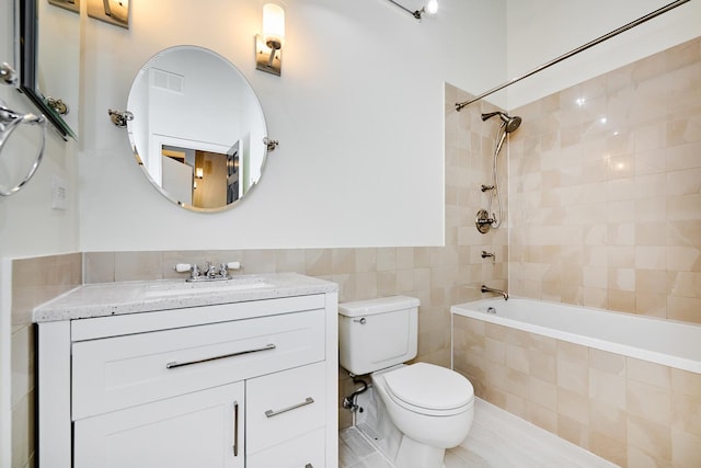 bathroom with visible vents, tile walls, toilet, tiled shower / bath combo, and vanity