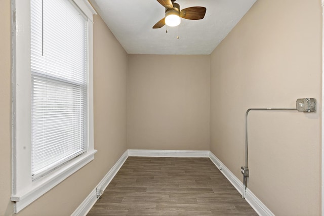 unfurnished room with a ceiling fan, plenty of natural light, wood finished floors, and baseboards