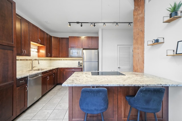 kitchen with tasteful backsplash, a breakfast bar area, appliances with stainless steel finishes, light tile patterned flooring, and a sink