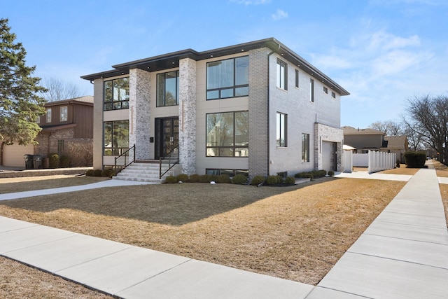 contemporary home with a garage, fence, a front yard, and brick siding