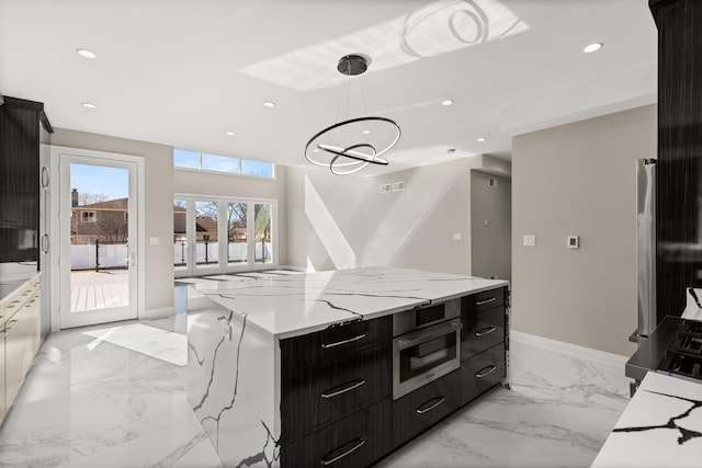 kitchen with oven, dark cabinetry, marble finish floor, a center island, and recessed lighting