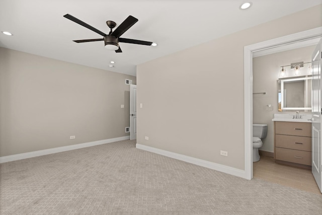 unfurnished bedroom featuring recessed lighting, a sink, light carpet, and ensuite bathroom