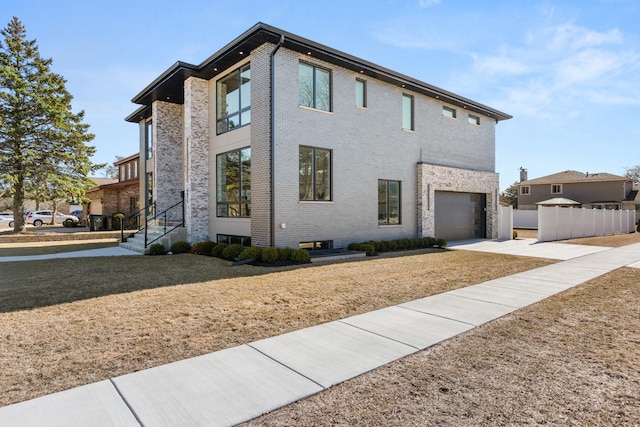 view of front of home with a garage, brick siding, fence, a front lawn, and concrete driveway