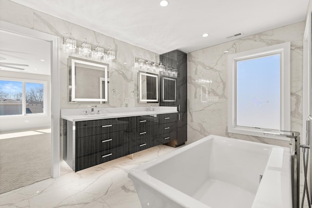 full bathroom with double vanity, visible vents, a sink, marble finish floor, and a soaking tub