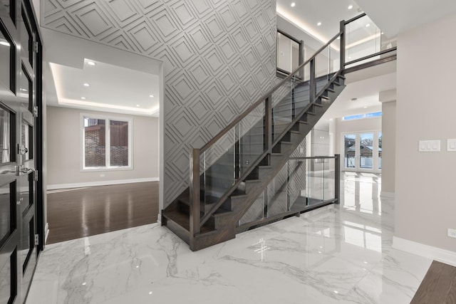 stairway with recessed lighting, baseboards, a high ceiling, and marble finish floor