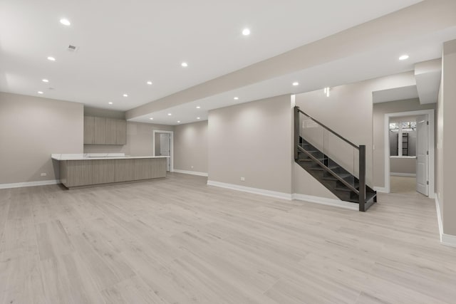 unfurnished living room featuring recessed lighting, baseboards, light wood finished floors, and stairs