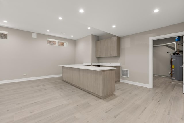 kitchen with water heater, baseboards, a kitchen island, visible vents, and modern cabinets