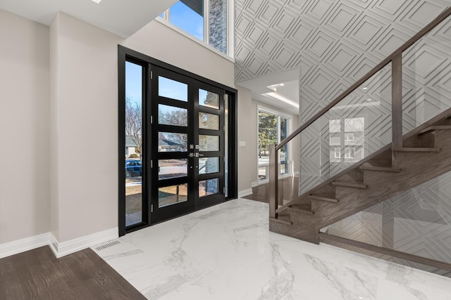 foyer featuring baseboards, french doors, stairs, and a towering ceiling