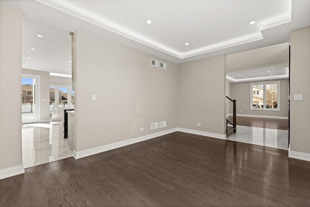 unfurnished living room featuring a raised ceiling, stairs, recessed lighting, wood finished floors, and visible vents
