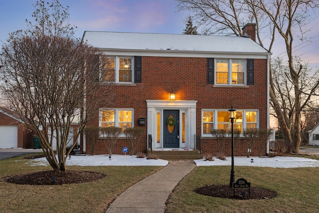 view of front of property featuring a front yard, brick siding, and a chimney