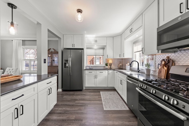 kitchen with dark countertops, a healthy amount of sunlight, appliances with stainless steel finishes, and a sink