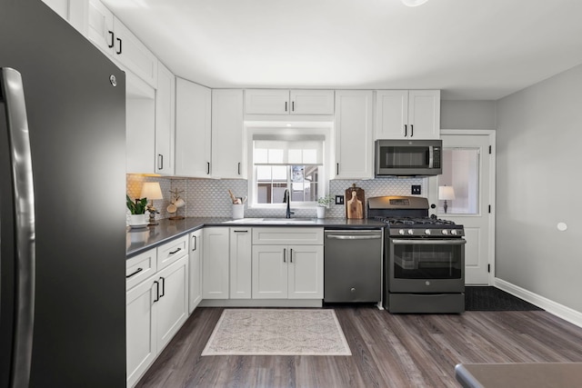 kitchen featuring dark wood finished floors, backsplash, appliances with stainless steel finishes, and a sink