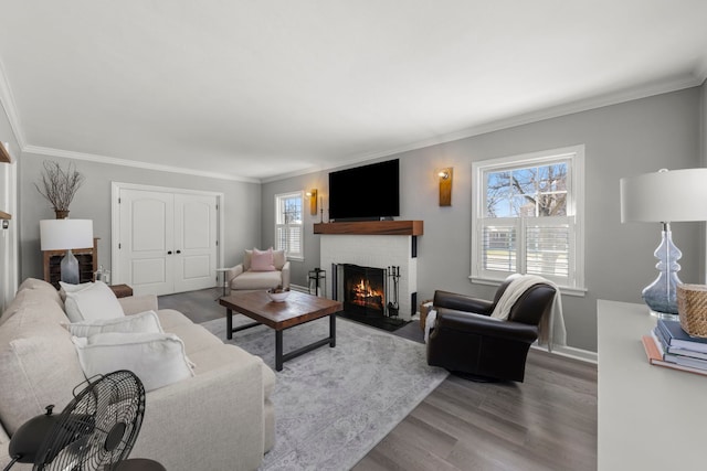living room with baseboards, wood finished floors, a fireplace, and ornamental molding