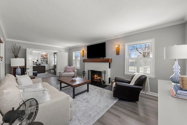 living room featuring a brick fireplace, wood finished floors, and ornamental molding